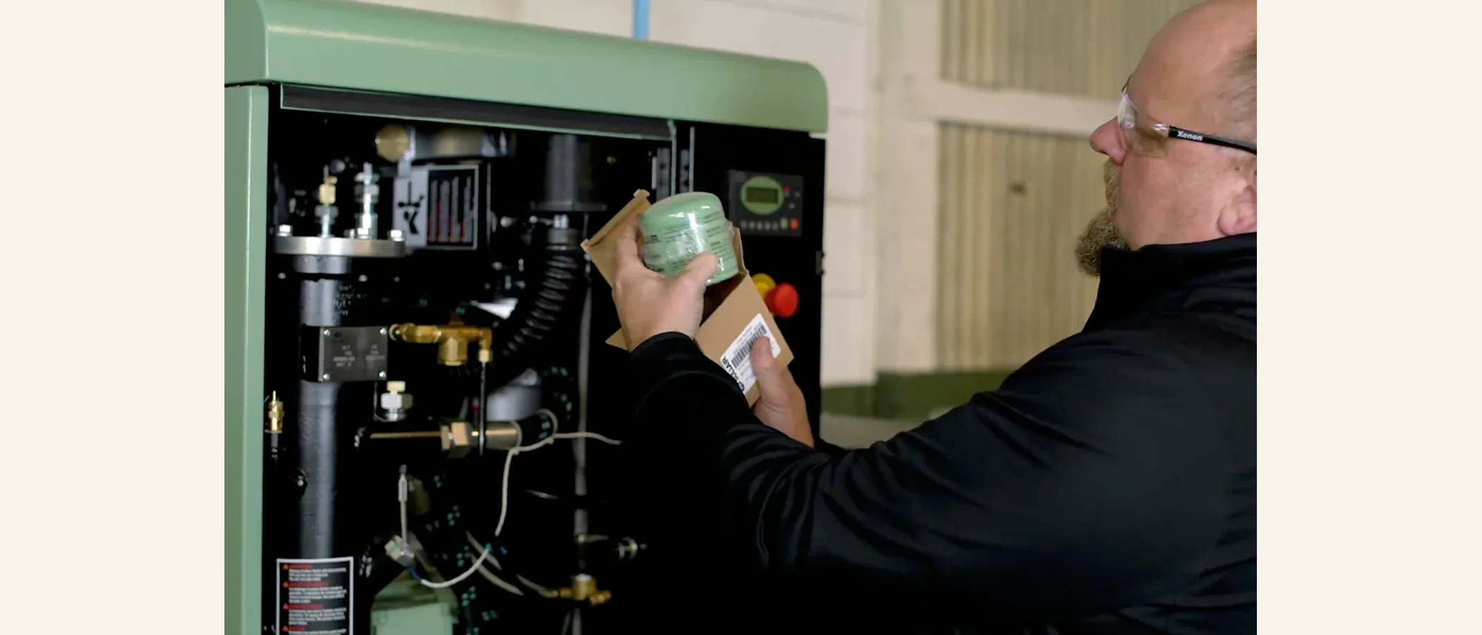 Technician inspecting a compressor oil filter inside a green machine