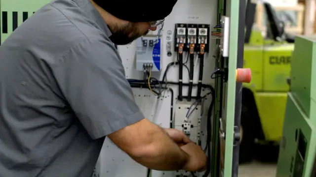 Technician repairing the electrical panel of a green industrial compressor