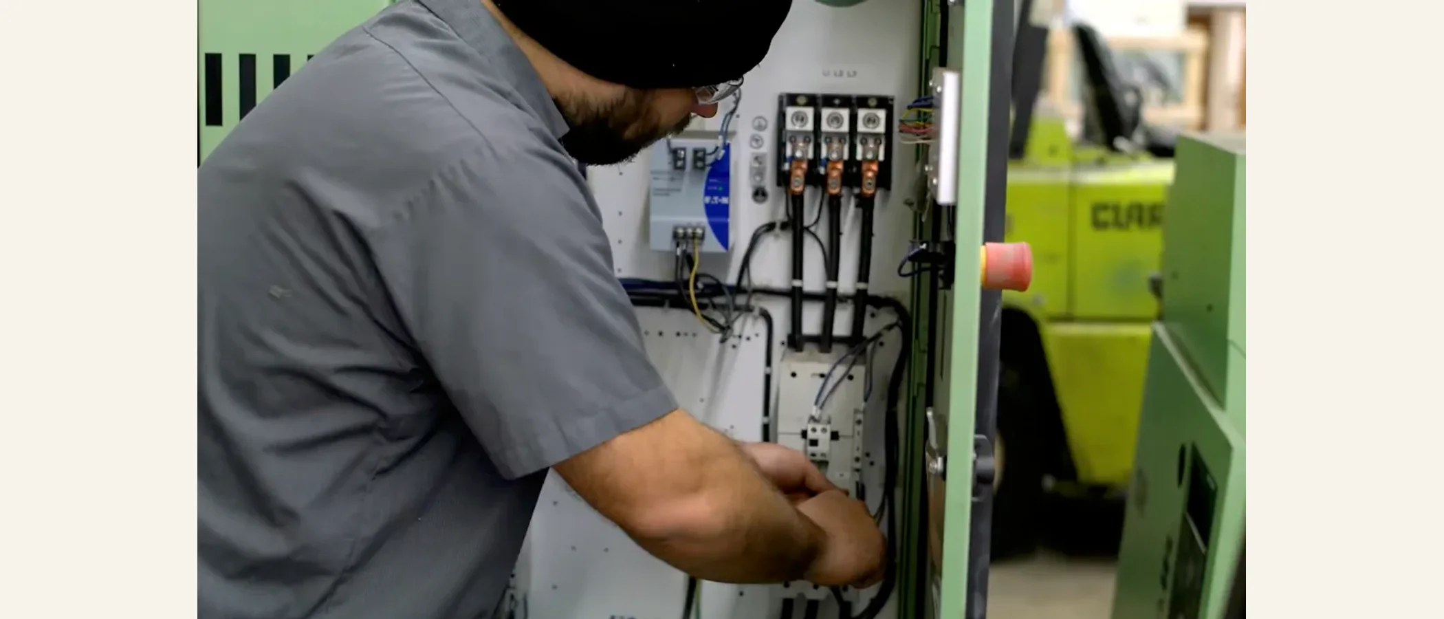 Technician repairing the electrical panel of a green industrial compressor