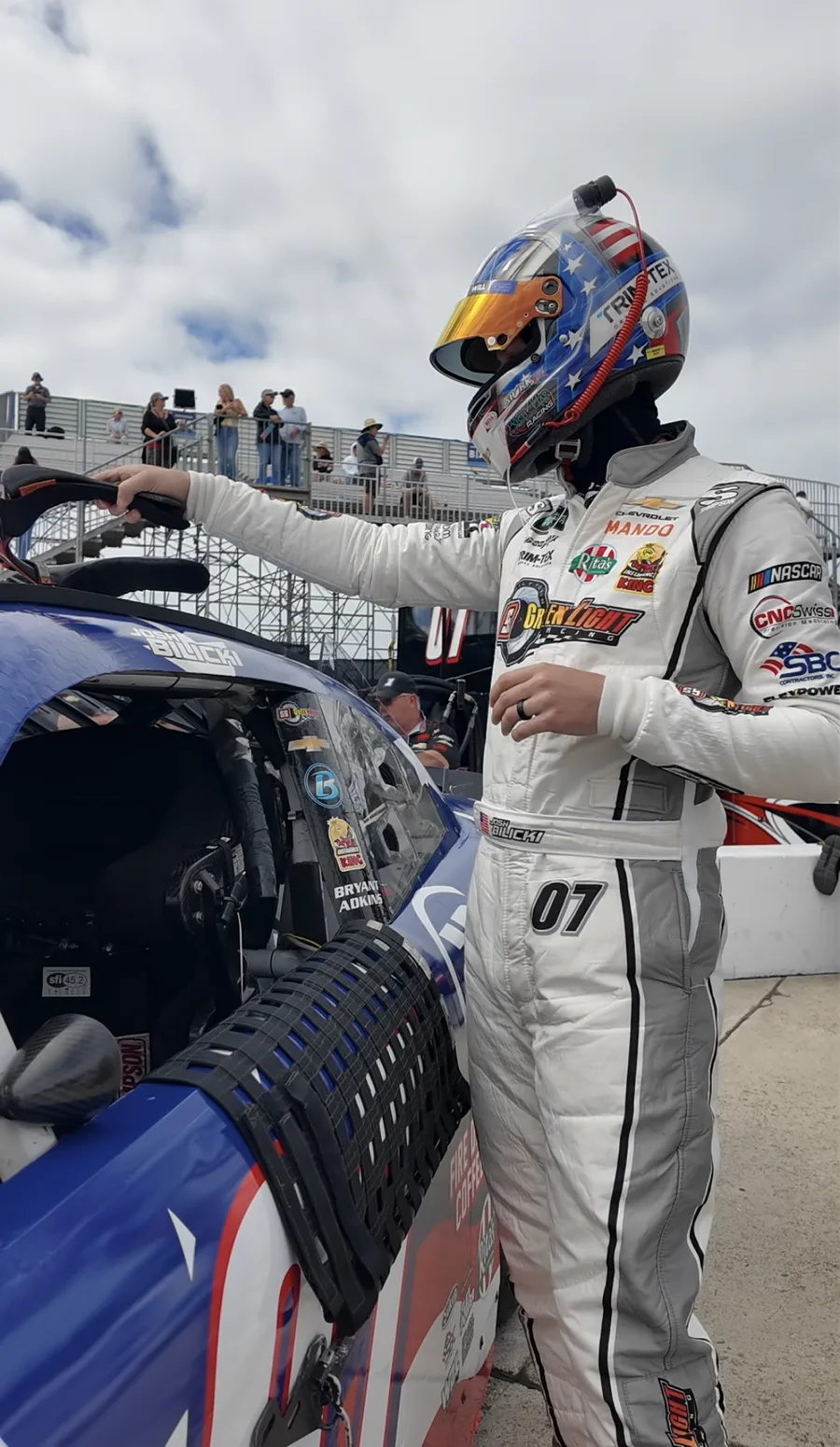 Josh Bilicki in his racing suit beside his car